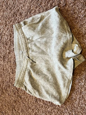 Grå mjukisshorts med snörning - Gråa mjukisshorts i bomull med elastisk midja och snörning. Klassisk loose fit och enkel design utan mönster eller logga. Perfekta för avslappnade dagar eller träning.