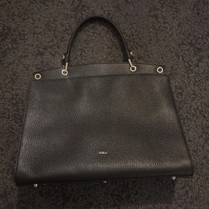 Svart Furla Väska  - En äkta väska från märker Furla, gjord av skinn. Knappt använd utan märken. Kommer med dess paket