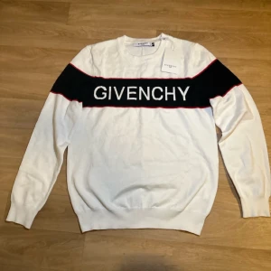  Givenchy tröja  - Snygg vit tröja från Givenchy med svart panel och röd kant över bröstet där loggan är broderad. Tröjan har rund halsringning och långa ärmar. M men passar även S