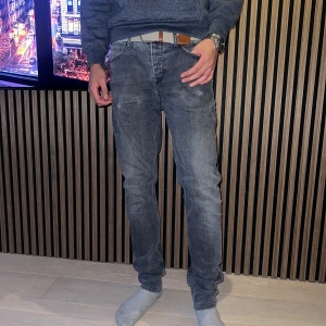 Grå jeans från Blue de Gênes - 31/34, Snygga grå jeans från Blue de Gênes, tillverkade i Italien. Jeansen har raka ben, klassisk femficksdesign och knäppning med metallknappar. Materialet är slitstarkt denim och färgen har en tvättad look med ljusare partier. Perfekta för dig som gillar stilrena och bekväma jeans.