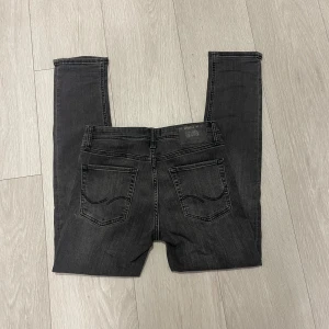 Svarta slim Glenn jeans från Jack and Jones  - Säljer ett par svarta slim jeans från Jack and Jones med klassisk. Jeansen har slimpassform och är tillverkade i stretchigt bomullsmaterial för extra komfort. Modell Slim Glenn 