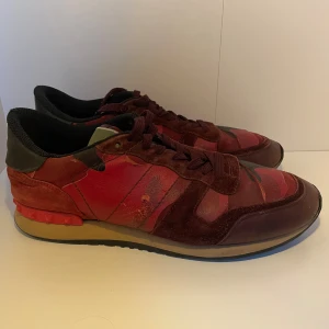 Valentino Garavani Rockrunner sneakers - Tja nu säljer vi dessa riktigt snygga Valentino Garavani Rockrunner sneakers i vinrött och rött med coolt kamouflagemönster. Skorna har detaljer i mocka och skinn, svarta och röda inslag samt klassiska nitar på hälen. Bekväm platt sula och snörning framtill. Perfekta för dig som gillar statement-sneakers. Perfekta till hösten där med! Skick 7/10 finns små defekter på skinnet men inget som syns när den används, box osv ingår ej!! Hör av dig vid minsta lilla fråga! ✨🌟