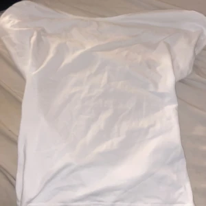 Vit kortärmad topp med bred hals - Säljer en enkel och fräsch vit topp med bred halsringning och korta ärmar. Toppen har en mjuk och slät yta, sydd i ett lätt material som känns skönt mot huden. Perfekt att styla med jeans eller kjol för en clean look.