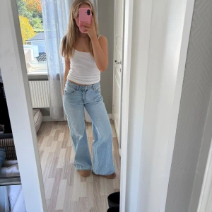 Ljusblåa wide jeans med hög midja - Säljer ett par ljusblåa jeans med hög midja och riktigt breda ben. Jeansen har klassisk femficksdesign och stängs med knapp och dragkedja. Perfekta för dig som gillar en avslappnad och trendig look.