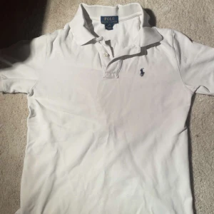 Ralph Lauren Piké - En vit pike från Ralph Lauren som tyvärr har små hål o slitningar på innersidan av kragen. Annars rätt fräsch!