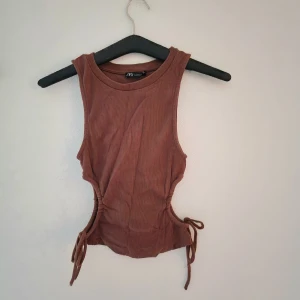 Brun ribbad linnetopp från Zara - Kamelfärgad cut-out topp i ribbat tyg. Toppensnygg, men den fick åka nu i flyttstädet.