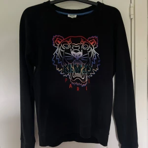Svart Kenzo sweatshirt  - En svart Kenzo sweatshirt Använts några gånger men ändå i ett bra skick. En snygg tröja med en unik logga på bröstet. Passar till typ allt och en perfekt tröja om man vill sticka ut med lite unika kläder. Storlek S, OBS säljer denna på Vinted också. Bara hör av er om ni har frågor!