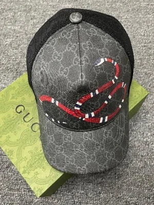 Grå Gucci keps med orm och GG-mönster - Säljer en grå keps från Gucci med klassiskt GG-mönster och en stor röd, vit och blå orm broderad på framsidan. Kepsen har svart mesh baktill och justerbar rem. Märkesdetaljer både på knapp och insida. Perfekt för dig som vill sticka ut.
