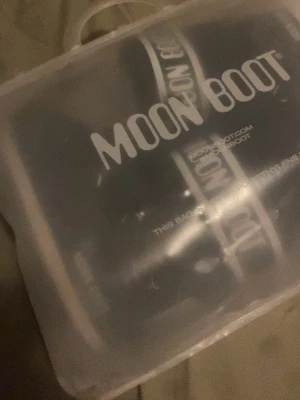 Svarta Moon Boot snow boots 36/38 - Säljer ett par klassiska svarta Moon Boot med vit logga och snörning. Bootsens insida är fodrad med mjukt syntetmaterial för extra värme och komfort. Perfekta för kalla vinterdagar och snöiga äventyr. det enda besväret på dessa skor är snöret annars är dom hur fina som helst använda få få gånger.