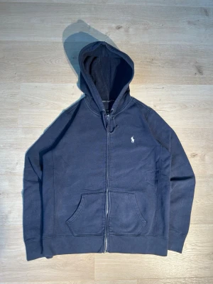 Blå Ralph Lauren Zip Hoodie - Klassisk Ralph Lauren hoodie i blå färg. | Tröjan är i mycket bra skick. Sparsamt använd :-)  | Storlek: S | Skick: Mycket bra skick! | : Blå | Märke: Ralph Lauren | Modell: Hoodie  | Hör gärna av dig vid frågor så svarar jag så fort jag kan! 😁 