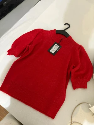 Röd stickad tröja från ONLY XS - Snygg röd stickad tröja från ONLY i modellen ONLCAMILLA. Puffiga ärmar och ribbade muddar ger en trendig look. Perfekt till höst och vinter när du vill ha något färgstarkt och mysigt. Materialet är mjukt och känns skönt mot huden.