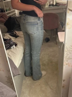 ljusblå bootcut jeans - Säljer ett par klassiska jeans i ljusblå tvätt. De har bootcut passform och låg midja, med en slitning på ena knät som jag gjort själv. Har inte använt jeansen många gånger 💕