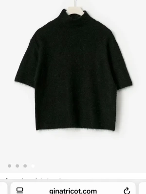 Svart polotröja från Gina Tricot - Mysig svart polotröja från Gina Tricot med korta ärmar och boxig passform. Tröjan är stickad i ett mjukt material och har en hög krage som ger en clean och stilren look. Perfekt att styla med jeans eller kjol.