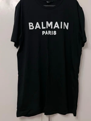 Svart t-shirt XL - Snygg svart t-shirt  i bomull med vit logga tryckt framtill. Klassisk passform med korta ärmar och rund hals. Perfekt för dig som vill ha en stilren och trendig look med exklusiv känsla.