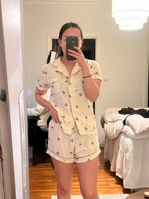 Pyjamas-set med nallemönster - Supergulligt pyjamasset i beige med små nallar och svarta prickar. Väldigt liten i storleken, skulle säga att det är typ en S, möjligen XS? Tunn i materialet