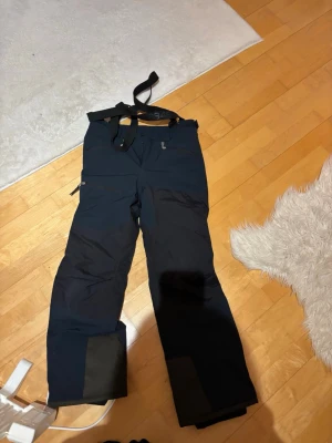 Svarta täckbyxor 8848 Altitude 160 - Säljer ett par svarta täckbyxor från 8848 Altitude i storlek 160. Byxorna har justerbara hängslen, flera dragkedjeförsedda fickor och förstärkta partier vid bensluten. Perfekta för vinterns alla äventyr och riktigt sköna att ha på sig.