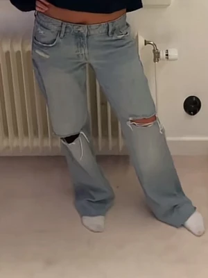Ljusblå jeans med slitningar - Säljer ett par ljusblå jeans med slitningar vid knäna från Zara. Perfekta för en avslappnad och trendig look.