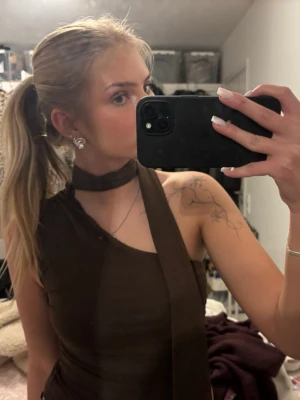 Brun oneshoulder topp med scarfdetalj - Säljer en brun oneshoulder topp med matchande scarfdetalj runt halsen. Toppen är tight och ärmlös.  