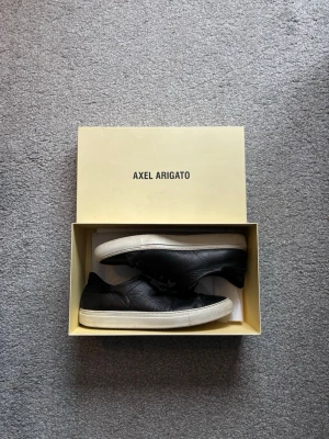 Svarta sneakers från Axel Arigato - Säljer ett par stilrena svarta sneakers från Axel Arigato som passar till det mesta! Box och påse ingår. Pris kan såklart diskuteras vid snabb affär.
