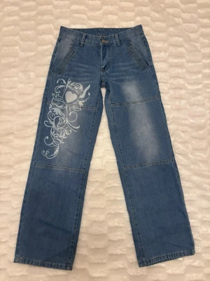 Jeans med tryck  - Super snygga jeans med ett tryck på ena benet, de är köpta från nån hemsida för nåt år sen som jag tyvärr inte kommer ihåg namnet på. De är aldrig använda och passar storlek 32-36💕