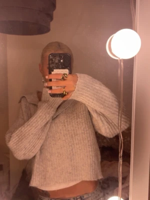 Ljusgrå stickad tröja från Gina Tricot - Supermysig ljusgrå stickad tröja från Gina Tricot med krage och v-ringning. Tröjan har en loose fit och långa ärmar, perfekt att slänga på sig till jeans. Ribbstickad och lite croppad modell.