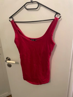 Röd linnetopp från Bershka - Säljer en enkel och snygg röd linnetopp från Bershka i storlek S. Toppen har breda axelband och en djup rundad urringning. Perfekt att styla till jeans eller kjol för en trendig look.