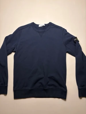 Mörkblå sweatshirt från Stone Island - Säljer en mörkblå crewneck från Stone Island med klassisk patch på vänster ärm. Storlek M men är som en S/M. Modellen på bilden är 177cm och väger ca 67kg.😊