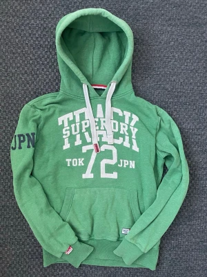 Vintage 2000s Superdry JPN hoodie (sällsynt) - Säljer nu denna sjukt snygga vintage 2000s superdry JPN hoodie! Passformen är helt perfekt och tröjan är i fint skick😊 Säljs ej längre i butik och är därav mycket eftertraktad 🙌 Skriv vid funderingar 📲