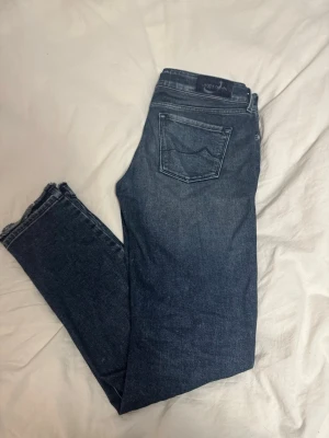 Jacob Cohen blå jeans, storlek 31 - Säljer ett par snygga blå jeans från Jacob Cohen i storlek 31. Jeansen har klassisk femficksdesign, raka ben med något smalare passform och råa, fransiga benslut. Tillverkade i mjukt denimtyg med diskret tvättad look och fina detaljer på insidan.