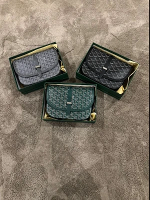  axelväska med grafiskt mönster - Finns i grönt, grått och svart med matchande läderdetaljer och metallspänne. Väskan har lock och justerbar rem, perfekt för dig som vill ha något stilrent och trendigt.