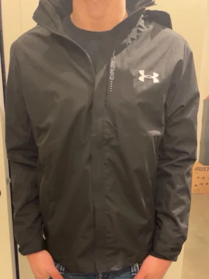 Svart under armour vindjacka - Tja! Säljer en fet under armour vindjacka! Storlek M. Nypris 1099kr. Modellen är 181cm och väger 70 kg.