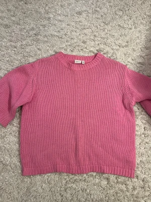 Rosa stickad tröja från Name It - Säljer en söt rosa stickad tröja från Name It i storlek 146-152. Tröjan har en klassisk rund halsringning och ribbade muddar vid ärmslut och nederkant. Perfekt för att hålla sig varm under kyligare dagar.💞💗