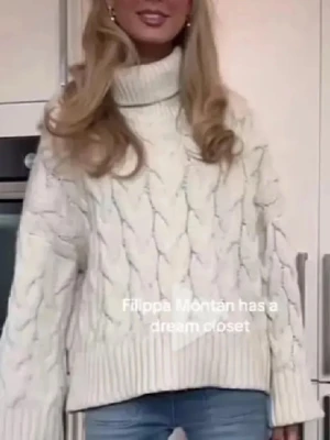 Vit polotröja med kabelstickning - Säljer en vit polotröja med grov kabelstickning och breda ribbade muddar. Tröjan har en hög krage och är långärmad med loose passform, perfekt för kyliga dagar. Materialet är stickad ullblandning som känns mjuk och varm.