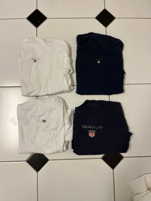 Gant t-shirts - Fyra stycken Gant T-shirts, två vita och två marin blå. Alla med broderade Gant märken en av de två marin blå har en större broderad logga samt större Gant.  Passar bra till personer som är runt 160cm.
