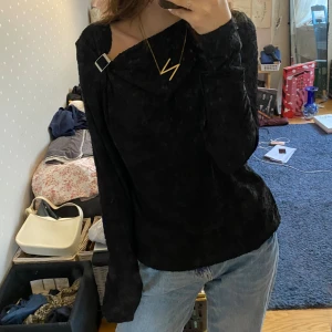 Svart långärmad topp från Sisters Point🖤 - Säljer en svart långärmad topp från Sisters Point med strukturmönstrad yta och en snygg detalj i form av ett silvrigt spänne vid halsen. Toppen har en lite lösare passform och är gjord i ett mjukt syntetmaterial som känns lyxigt. Storleken är XL men passar mig som har S 🖤