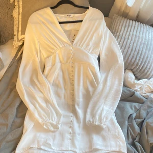 Vit kort klänning från NA-KD - Superfin vit kort klänning från NA-KD, perfekt till sommaren eller som studentklänning!🌸😍          Med v-ringning och långa puffärmar. Gjord i ett lätt, flowy material som är perfekt till sommaren!    Nypris: 699