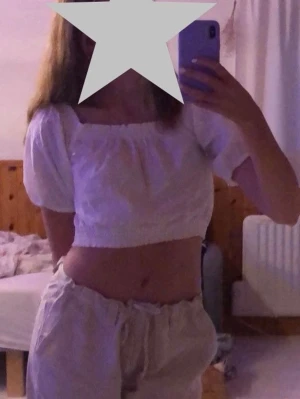 Vit croppad blus från H&M Divided - Vit croppad blus från H&M Divided med korta puffärmar och broderade detaljer. Toppen har resår både vid midjan och ärmsluten. 