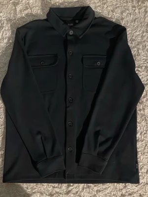 Overshirt/Cardigan från Only & Sons - Snygg svart overshirt från ONLY SONS i storlek M. Den är helt oanvänd skick: 10/10. Perfekt att slänga på över en hoodie eller t-shirt för en clean look. Materialet känns mjukt och har en stilren finish. Anledningen varför jag säljer den är för att den är för stor för mig. Fråga om du undrar över nåt.