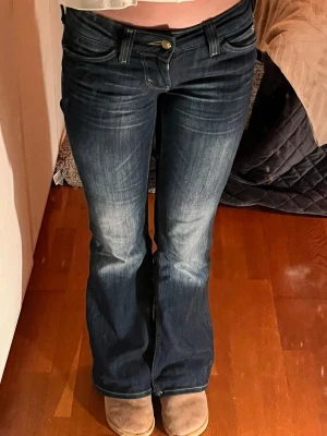 Mörkblå low waist bootcut jeans från Cheap Monday  - Säljer ett par mörkblå jeans från Cheap Monday med bootcut passform och låg midja. Jeansen har snygga slitningar framtill, klassiska fem fickor och kontrastsömmar. Perfekta för dig som gillar retrovibbar och markerad siluett. Tyvärr sticker det ut två ihop snurrade trådar på höger framsida ( se bild 4) men det syns nästan inte.