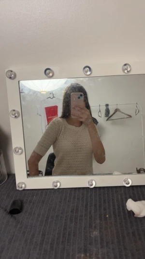 Beige stickad topp med kort ärm - Säljer en beige stickad topp med korta ärmar och rund hals. Toppen har ett snyggt hålmönster som ger en luftig känsla och passar perfekt till både jeans och kjol. Enkel och stilren design som är lätt att matcha.