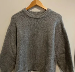 Grå stickad tröja från BikBok - Mysig grå stickad tröja från BikBok i storlek XS. Tröjan har en rundad hals och ribbade muddar vid ärmslut och nederkant. Perfekt för kyliga dagar och enkel att matcha med jeans eller kjol.Har rosa fläckar som kan gå bort men vet ej