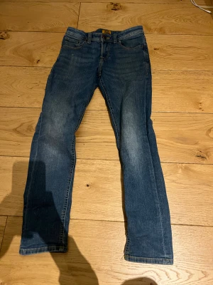 Blå Jack and Jones Jeans - JACK & JONES Blå Jeans –   Blå jeans från Jack & Jones i storlek 146 (ca 11 år). Slim fit-modell i mycket fint skick utan fläckar eller hål. Sitter bra, bekväma och hållbara.