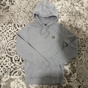 Grå hoodie från Lyle & Scott - Snygg grå hoodie från Lyle & Scott med klassisk gul logga på bröstet. Den är i jätte bra skick och passar till allt, den är i storlek xs men passar också s