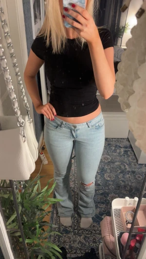 Low waist jeans - Säljer ett par ljusblå jeans med bootcut passform och låg midja. Jeansen har slitning vid knät och fint rosa broderi på bakfickorna. 