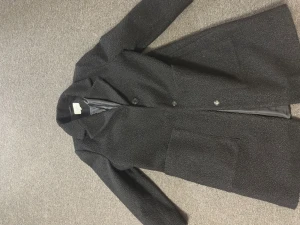 Svart teddyrock från Isolde, stl 40 - Svart teddyrock från Isolde i storlek 40. Jackan har en fluffig teddystruktur, stora fickor framtill och stängs med knappar. Tillverkad i 100% polyester och har en klassisk krage. Perfekt för dig som gillar en stilren och mysig look.