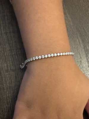 Silverfärgat tennisarmband Daniel Wellington - Snyggt tennisarmband från Daniel Wellington i silverfärg med gnistrande runda stenar längs hela länken. Armbandet har en tunn och elegant form, justerbar kedja och DW-graverad bricka vid låset. Perfekt för dig som gillar stilrena smycken med lite bling.