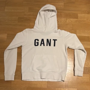 Vit hoodie från GANT - Riktigt fin hoodie som jag nu ska sälja! Fin med gant tryck lite under bröstet i mörk blått. Väldigt bra skick! Hoodien har en ficka vid lägre delen av magen som klassiska hoodies har! Skriv vid minsta tanke eller fråga!