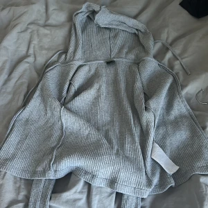 Grå ribbad hoodie från Gina Tricot - Säljer en grå kofta från Gina tricot.Den är i bra skick och har inte andvänds särskilt mycket.Den är skön och har en bra passform.Inga tecken på hål 