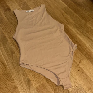 Beige body från zara - Säljer en stilren beige body topp från Zara. Toppen har en tight passform och är tillverkad i mjukt, stretchigt material som sitter snyggt mot kroppen. Perfekt att styla med jeans eller kjol. Sitter mer som en S