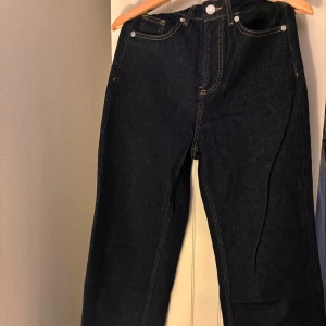 Mörkblå jeans från Vero Moda - Snygga mörkblå jeans från Vero Moda med klassisk femficksdesign och kontrastsömmar. Modellen har hög midja och vida ben för en tidlös look. 